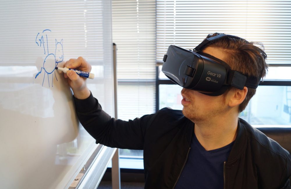 Person Wearing Black Vr Box Writing On White Board