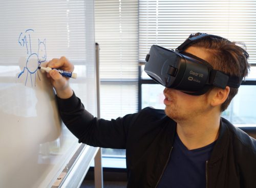 Person Wearing Black Vr Box Writing On White Board