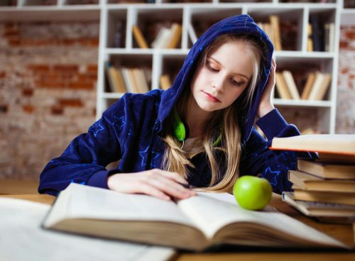 Woman Wearing Blue Jacket Sitting on Chair Near Table Reading Books