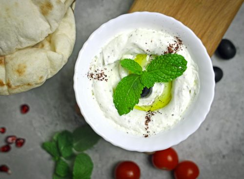 A bowl of yogurt with olives and mint leaves