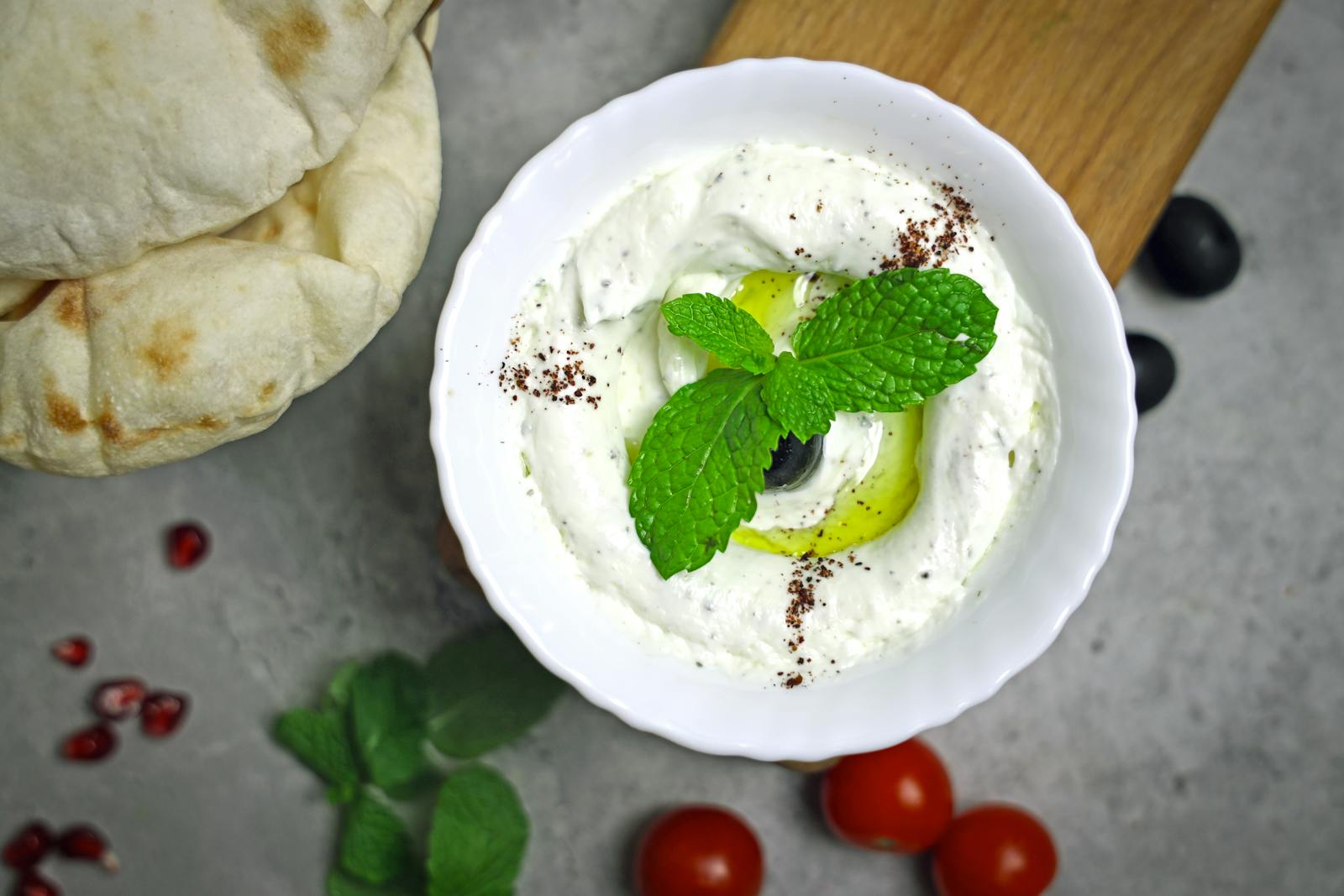 A bowl of yogurt with olives and mint leaves
