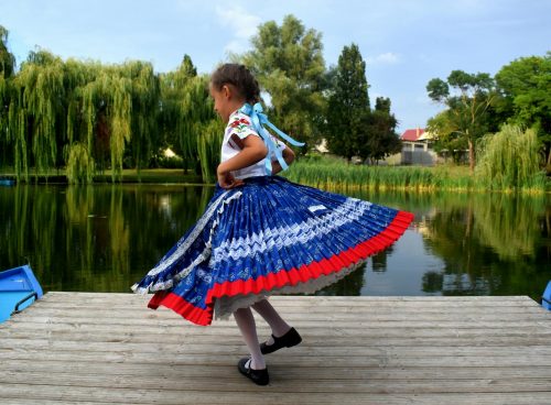 Little Girl Wearing Traditional Clothing Dancing on a Lakeshore Jetty