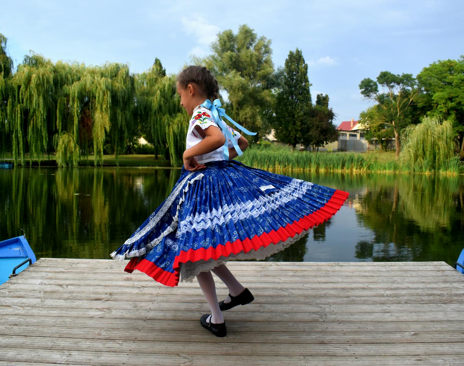 Little Girl Wearing Traditional Clothing Dancing on a Lakeshore Jetty