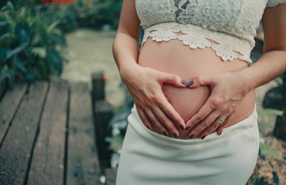 Pregnant Woman Wearing White Skirt Holding Her Tummy