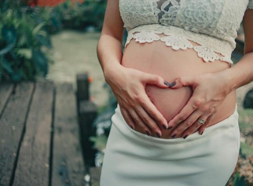 Pregnant Woman Wearing White Skirt Holding Her Tummy