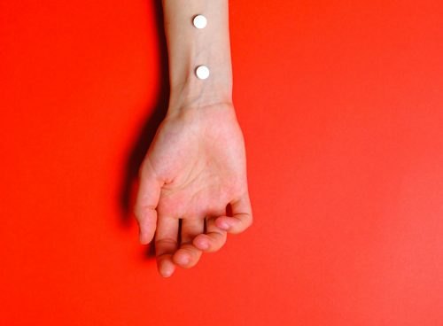 Photo of Person's Arm on Red Background