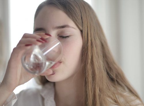 Woman in White Shirt Drinking Water From Clear Glass with Her Eyes Closed