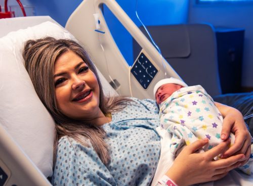 A woman holding a baby in a hospital bed