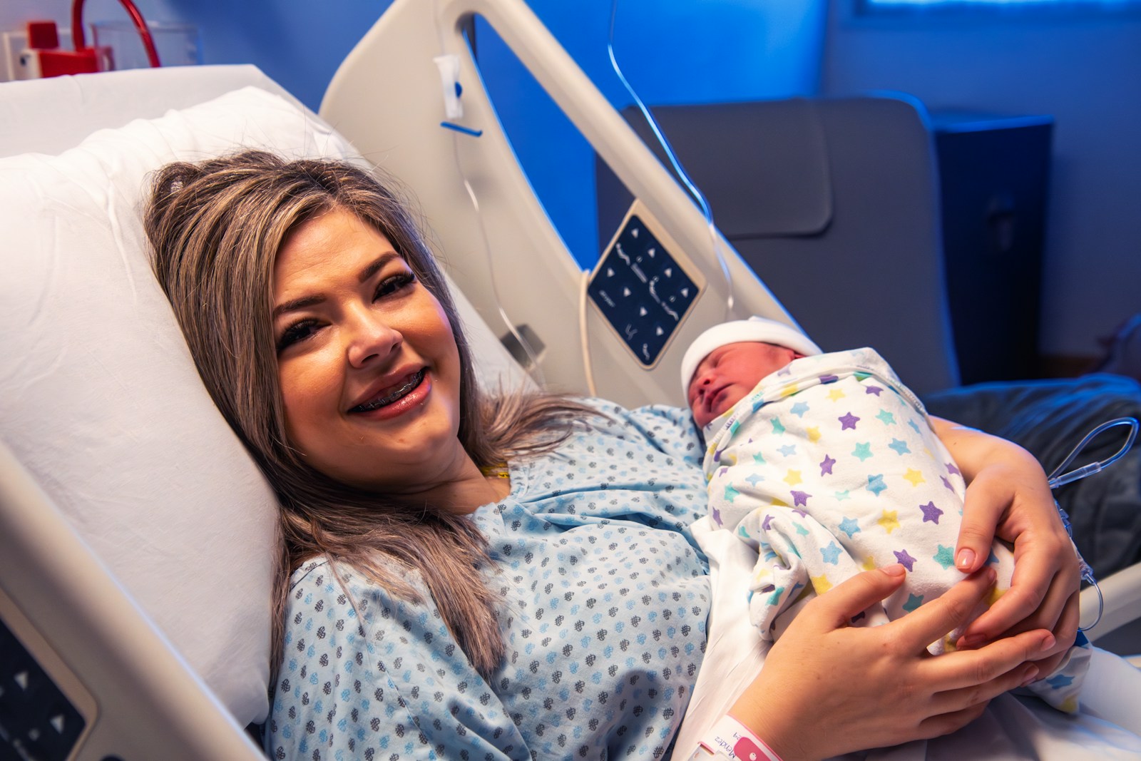 A woman holding a baby in a hospital bed