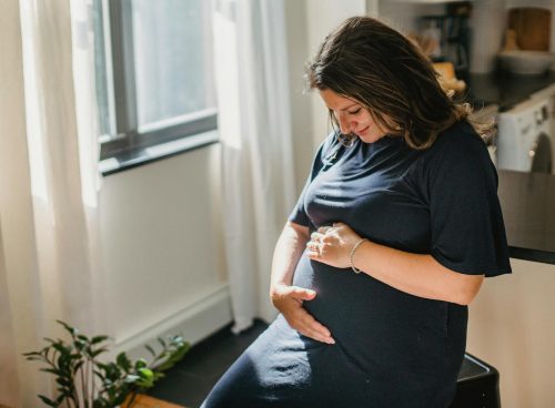 Cheerful pregnant woman touching belly