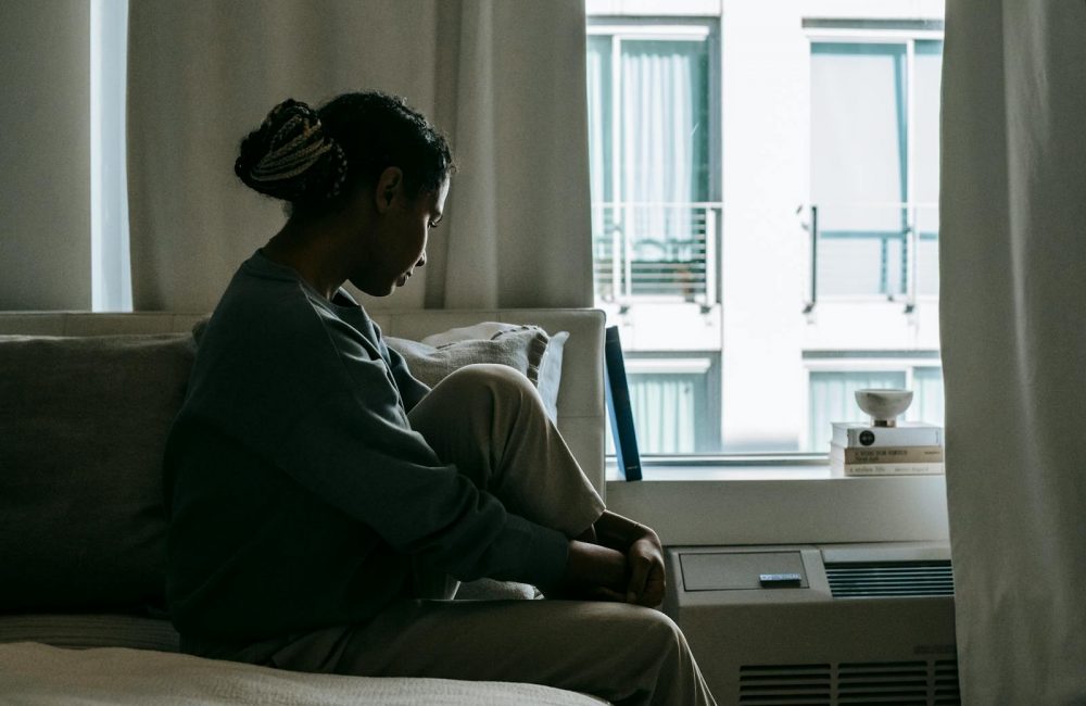 Upset black woman on bed in house