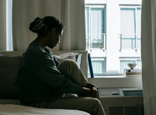 Upset black woman on bed in house