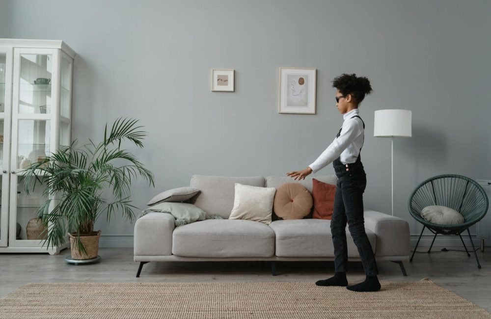 A Child Wearing Sunglasses Walking on a Rug Beside a Sofa