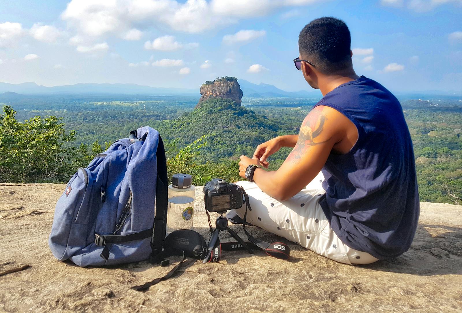 15 Must-Visit Destinations for Single Men 1 Man Sitting on Top of Gray Cliff Mountain Beside Backpack, Water Bottle, and Camera
