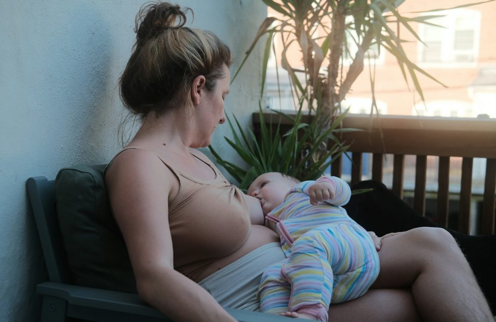 a woman sitting on a bench holding a baby