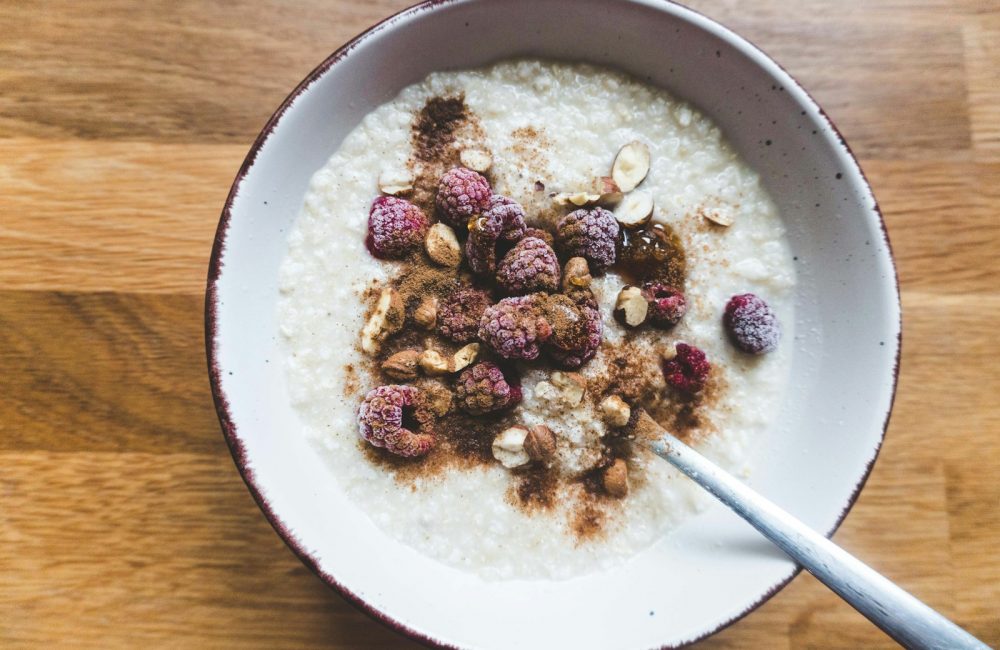 a bowl of oatmeal topped with raspberries and nuts