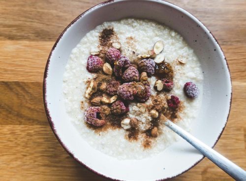 a bowl of oatmeal topped with raspberries and nuts