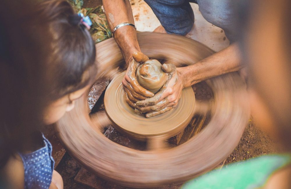 person molding clay while children are watching at daytime