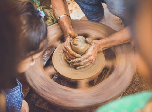 person molding clay while children are watching at daytime