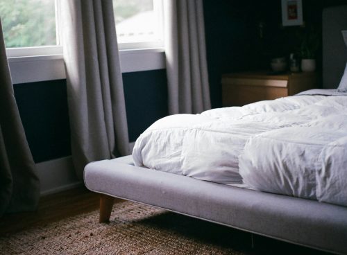 white bed by the window during daytime