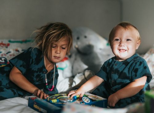 girl in blue and black crew neck t-shirt sitting beside white polar bear plush toy
