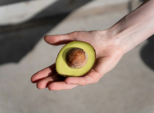 a person holding an avocado in their hand