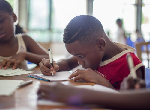 boy writing on printer paper near girl