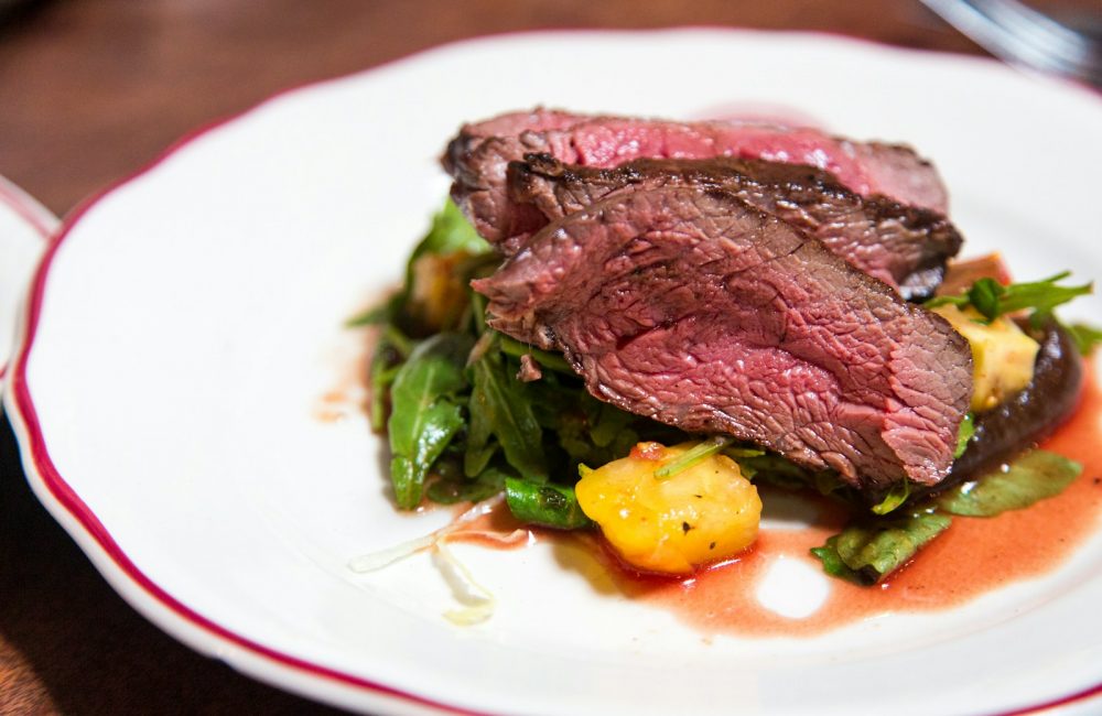 medium rare sliced steak in white ceramic plate
