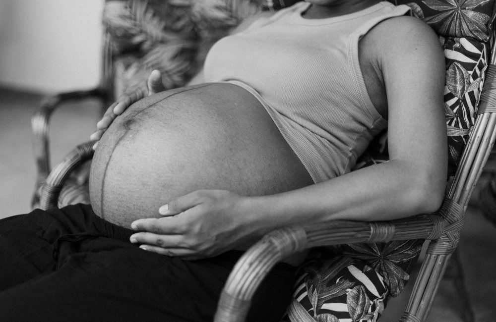 a black and white photo of a pregnant woman sitting in a chair