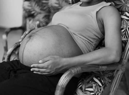 a black and white photo of a pregnant woman sitting in a chair