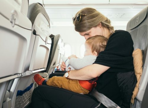 woman carrying baby while sitting on gray seat