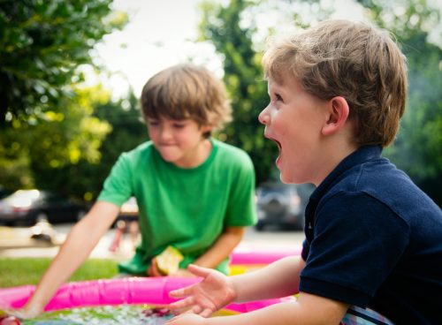 boy in blue shirt screaming near boy in green crew-neck shirt