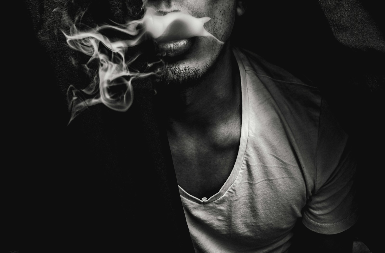 Does Smoking Cause Hair Loss? Understanding the Link Between Smoking and Hair Thinning 1 man wearing white V-neck shirt with smoke coming out of mouth