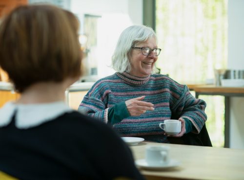 a woman sitting at a table talking to another woman