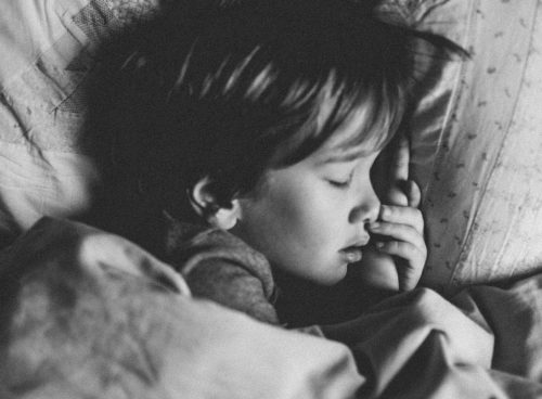 grayscale photo of girl sleeping on white pillow