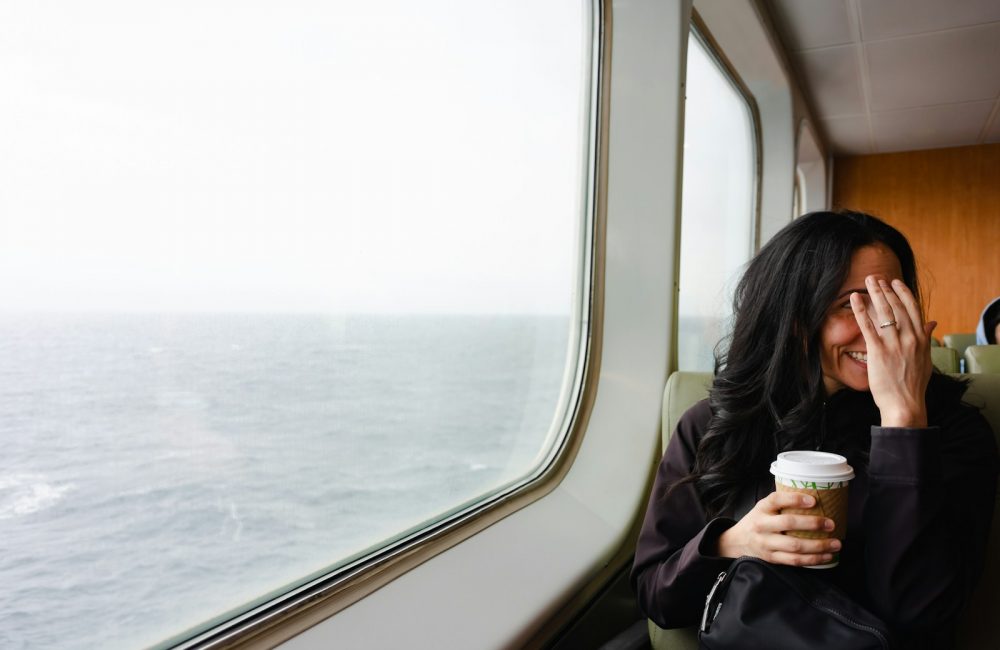 a woman sitting on a train holding a cup of coffee
