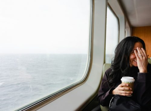 a woman sitting on a train holding a cup of coffee