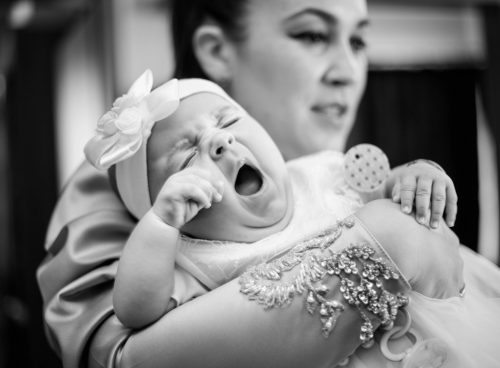 man in gray shirt carrying baby in grayscale photography