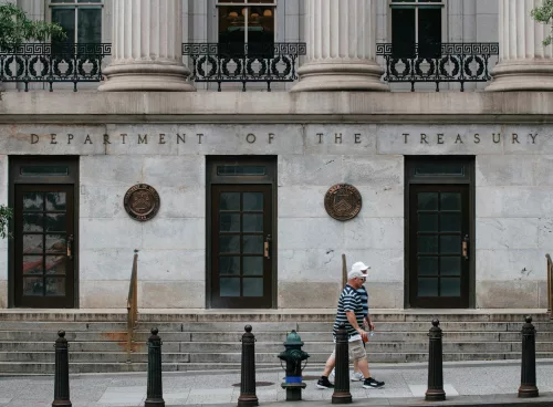 Two people walking down a street past a tall building